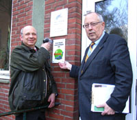 Bezirksamstleiter Torsten Meinberg und Rolf de Vries bringen das NUE-Schild beim HARBURG21-Büro an. (Foto Gisela Baudy)
